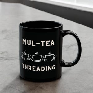 May include: Black ceramic mug with the text "MUL-TEA THREADING" in white, along with three stylized teacup illustrations. The mug has a large handle and is set against a neutral background.