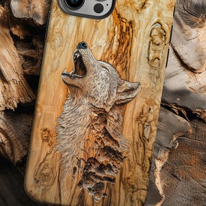 Puede incluir: Una funda para teléfono con un diseño de madera tallada que presenta un lobo aullando a la luna. La funda es marrón y tiene un patrón de veta de madera natural.