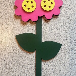 May include: A pink flower with three yellow centers, each with six holes, on a green stem with two leaves.