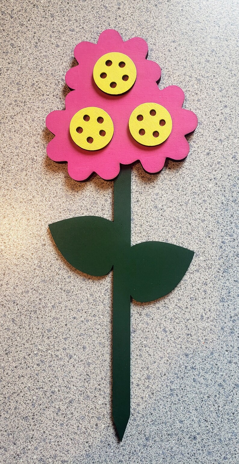 May include: A pink flower with three yellow centers, each with six holes, on a green stem with two leaves.