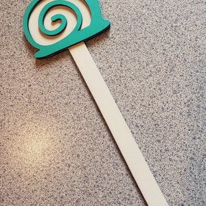 May include: A teal wooden snail garden stake with a white stick. The snail has a spiral shell.