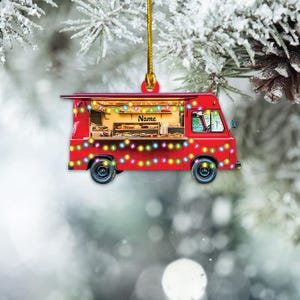 May include: Red food truck ornament with string lights and the word "Name" on the side. The truck is decorated with colorful lights and is a festive Christmas ornament.