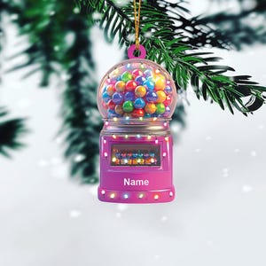 May include: Pink gumball machine Christmas ornament with colorful gumballs and lights. The ornament has the word "Name" on the front.