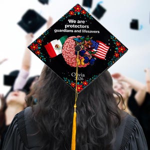 May include: A black graduation cap with a colorful design. The cap features the text "We are protectors guardians and lifesavers", a brain graphic, and the flags of Mexico and the United States. The name "Olivia" and the year "2026" are also displayed.