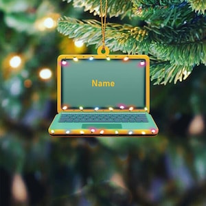 May include: A yellow laptop ornament with a green screen and a keyboard. The screen has the word "Name" on it. The laptop is decorated with colorful lights.