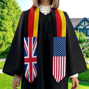 May include: A black graduation gown with a sash featuring the flags of the United Kingdom, Germany, and the United States.