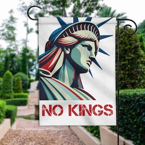 May include: A garden flag featuring a stylized illustration of the Statue of Liberty with a tear, in shades of blue, red, and white. The flag has the words "NO KINGS" in red block letters.