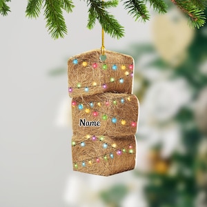 May include: A brown hay bale Christmas ornament with colorful lights wrapped around it. The ornament has the word "Name" written on it.