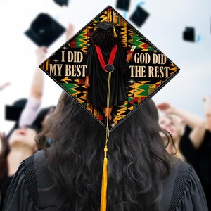 May include: A graduation cap with a black, green, and yellow patterned design. The cap features the text "I DID MY BEST" and "GOD DID THE REST". A black figure in a graduation gown is depicted on the cap, with a red sash and a gold tassel.
