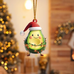 May include: A green avocado ornament with a red Santa hat and a smiling face. The avocado is decorated with a string of red Christmas lights.