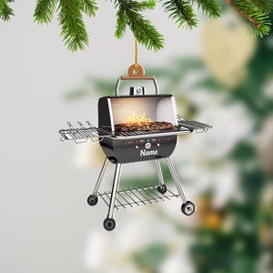 May include: Black and silver grill ornament with a flame inside and the word "Name" on the front.