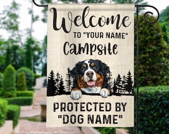 May include: Welcome to "YOUR NAME" Campsite, protected by "DOG NAME". A Bernese Mountain Dog peeks out from behind a silhouette of trees. The flag is beige with brown text.