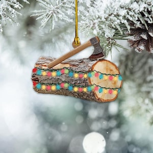 May include: A Christmas ornament shaped like a log with an axe and string lights. The log is brown with a rough texture, and the axe has a wooden handle and a silver blade. The string lights are multicolored.