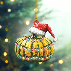 May include: A yellow pumpkin with a red Santa hat and colorful Christmas lights wrapped around it. The pumpkin is a Christmas ornament.