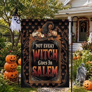 May include: A rectangular garden flag with a black background featuring a repeating orange jack-o'-lantern pattern. The center displays a witch hat, pumpkins, and spiderwebs with the text "NOT EVERY WITCH LIVES IN SALEM" in orange and red.