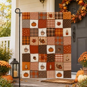 May include: A rectangular garden flag featuring a patchwork design of autumn-themed squares in shades of orange, brown, and cream. The pattern includes illustrations of pumpkins, coffee mugs, candles, maple leaves, acorns, and cornucopias.