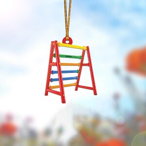May include: A red, yellow, green, and blue wooden climbing frame with the word "Name" printed on it. The frame is hanging from a yellow rope.