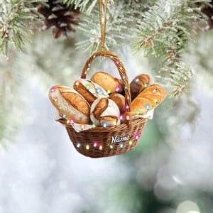 May include: A brown wicker basket filled with bread loaves, decorated with colorful lights and the word "Name" on the side. The basket is hanging from a Christmas tree.
