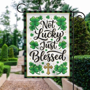 May include: A garden flag with a white background, green shamrocks, and the text "Not Lucky Just Blessed" in black script. The flag has a gold cross and is framed with a green and black plaid border.