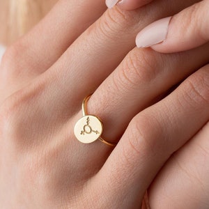 May include: A gold ring with a small round disc featuring a gender symbol.