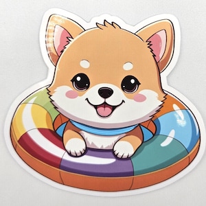 May include: A die-cut sticker featuring a cartoon Shiba Inu puppy with tan and white fur, large black eyes, and pink cheeks. The puppy is positioned inside a colorful, multi-segmented inflatable swim ring with orange, blue, and purple sections.