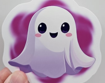 May include: A die-cut sticker featuring a cartoon ghost with a white body, large black eyes, a smiling mouth, and small pink circular cheeks. The ghost is set against a soft, blurred magenta purple background, creating a vibrant contrast.