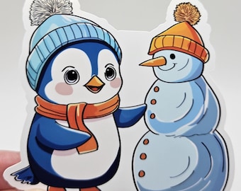 Pegatina de pingüino kawaii construyendo un muñeco de nieve – Vinilo decorativo invernal adorable