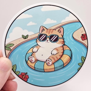 Peut inclure: Un autocollant circulaire représentant un chat tigré orange de dessin animé portant des lunettes de soleil noires, flottant dans une piscine bleue sur une bouée rayée jaune et bleue, entouré d'hibiscus rouges et de feuilles vertes sous un ciel bleu.