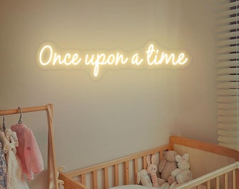 May include: A white neon sign with the text "Once upon a time" on a light beige wall above a wooden crib with stuffed animals inside.