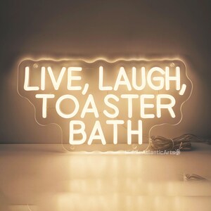Puede incluir: Un letrero de ne&oacute;n blanco con el texto "Live, Laugh, Toaster Bath" sobre un fondo blanco.
