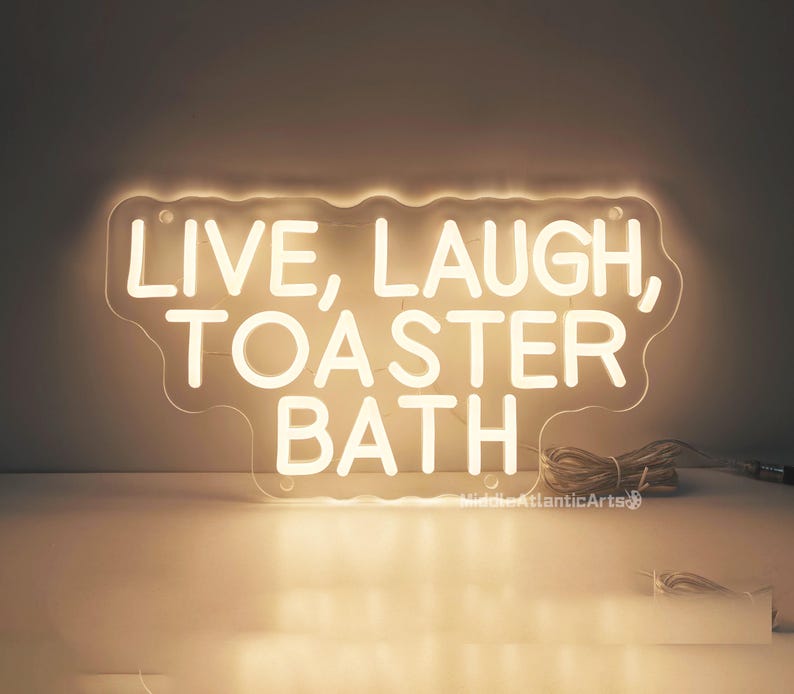 Puede incluir: Un letrero de ne&oacute;n blanco con el texto "Live, Laugh, Toaster Bath" sobre un fondo blanco.