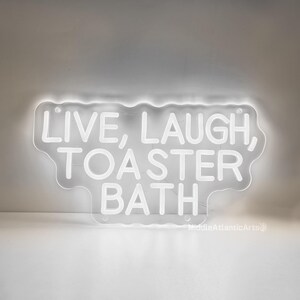 Puede incluir: Un letrero de ne&oacute;n blanco con el texto "Live, Laugh, Toaster Bath" en forma de nube.