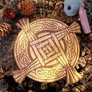 May include: A wooden Celtic knot design with a woven pattern in the center. The knot is carved into a round piece of wood and has a brown stain finish.