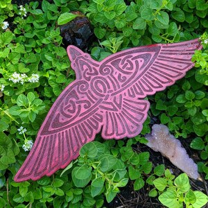 May include: A pink and red decorative bird with intricate patterns carved into its surface. The bird is made of wood and has a rustic, vintage look.
