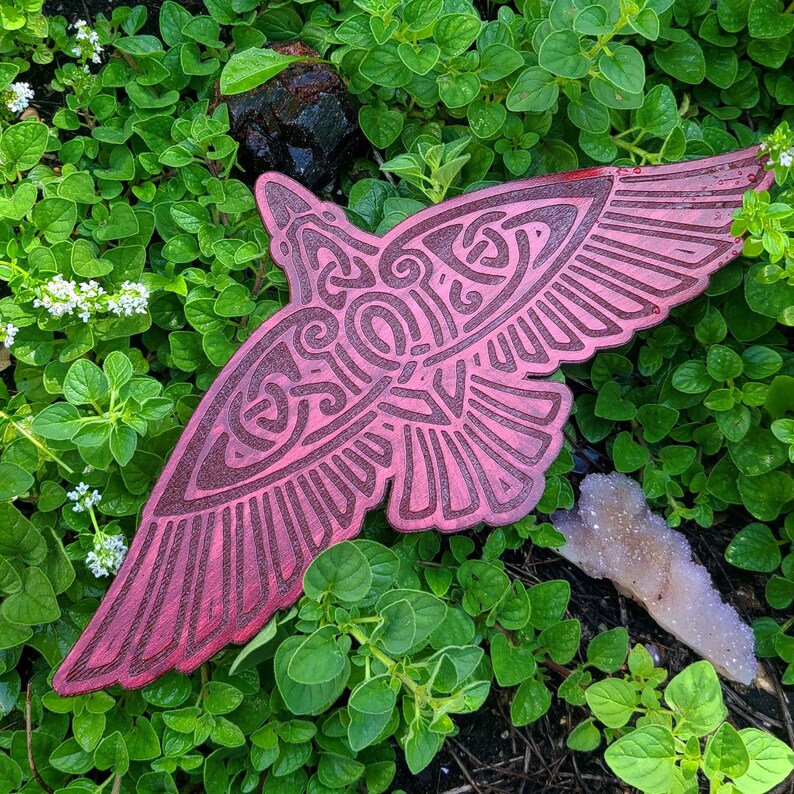 May include: A pink and red decorative bird with intricate patterns carved into its surface. The bird is made of wood and has a rustic, vintage look.
