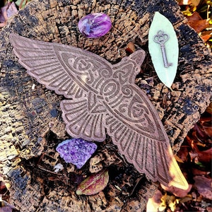 May include: A wooden carving of a bird with intricate details, set on a tree stump with purple amethyst crystals and a key on a green leaf.