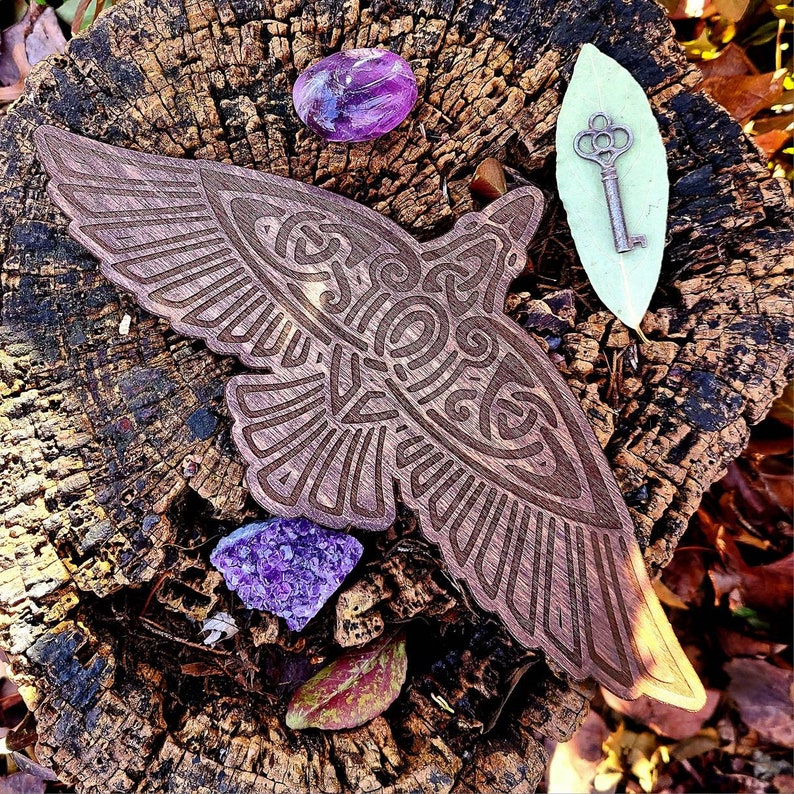 May include: A wooden carving of a bird with intricate details, set on a tree stump with purple amethyst crystals and a key on a green leaf.