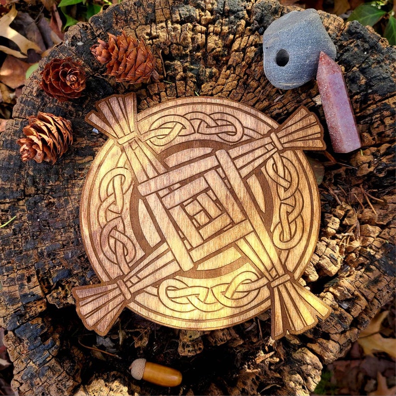 May include: A wooden Celtic knot design with a woven pattern in the center. The knot is carved into a round piece of wood and has a brown stain finish.