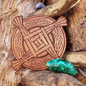 May include: A wooden Celtic knot design with a brown finish. The knot is in the shape of a cross with a square in the centre. The knot is surrounded by a circle of smaller knots. The design is on a wooden background.