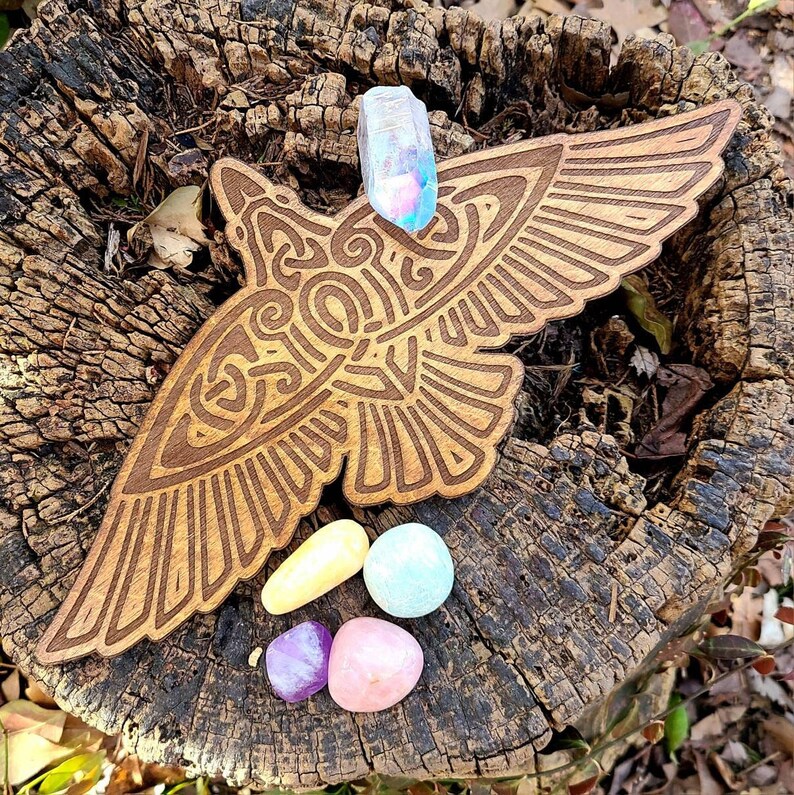 May include: A wooden carving of a bird with intricate details, resting on a tree stump.  Four colorful crystals are placed on the bird's wings.