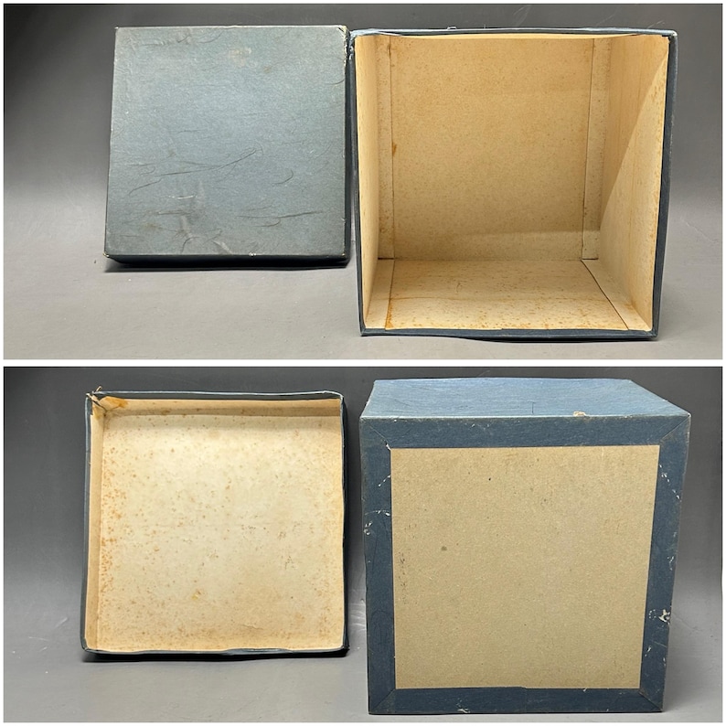 K&ouml;nnte beinhalten: Zweiteilige, blaue Vintage-Box mit Deckel. Die Box ist quadratisch mit hellblauem &Auml;u&szlig;eren und beigem Innenraum. Der Deckel ist abgenommen und gibt den Blick auf das Innere der Box frei. Die Box ist wahrscheinlich aus Pappe oder einem &auml;hnlichen Material.