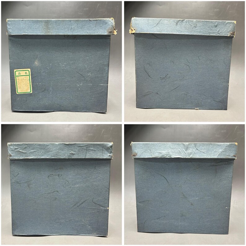K&ouml;nnte beinhalten: Vier Ansichten einer quadratischen, blauen Box mit Deckel. Die Box hat eine strukturierte Oberfl&auml;che und ein Etikett auf einer Seite. Die Box scheint aus Papier oder Pappe zu bestehen. Die Box ist wahrscheinlich f&uuml;r die Aufbewahrung oder Verpackung bestimmt.