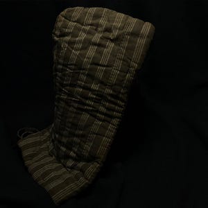 May include: A quilted oven mitt in a dark olive green color with vertical stripes in a lighter shade. The mitt has a loop for hanging and is designed to protect hands from heat.