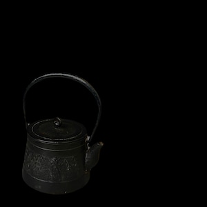 Puede incluir: Una tetera de hierro fundido negro con un asa curva y un pequeño pico. La tetera tiene una superficie texturizada con un diseño floral. La tapa tiene un pequeño pomo. Ideal para preparar té.