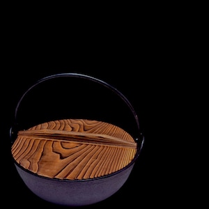 Puede incluir: Una taza de cerámica blanca con un asa negra y el texto "But First, Coffee" en negro y negrita. La taza está sobre una superficie de madera.
