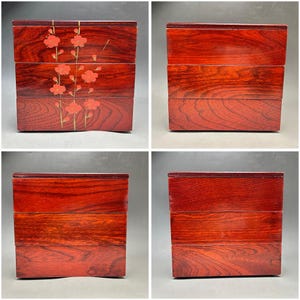 K&ouml;nnte beinhalten: Vier Bilder einer gestapelten Bento-Box aus Holz. Die Box ist tiefrotbraun mit gl&auml;nzendem Finish. Eine Box zeigt ein Blumendesign mit roten Bl&uuml;ten und goldenen Akzenten. Die anderen Boxen sind schlicht. Die Box wird wahrscheinlich zum Transport von Lebensmitteln verwendet.