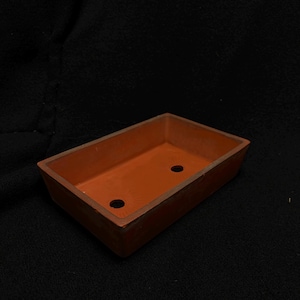 以下が含まれることがあります： わずかに先細りのデザインの、長方形のテラコッタ色のプランター。 プランターの底には2つの排水穴があります。 内面と外面は均一な赤茶色です。