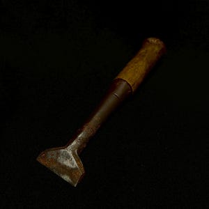 May include: An antique tool with a wooden handle and a metal blade. The blade is rectangular and shows signs of rust. The handle is made of wood. The tool has a dark brown, aged appearance.