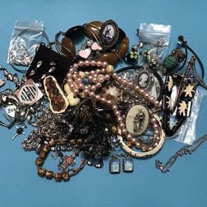 Puede incluir: Una gran colección de bisutería variada que incluye un collar de perlas rosas, varias cadenas de metal, pulseras, colgantes de camafeo, pendientes y accesorios de cuentas, algunas piezas están empaquetadas en pequeñas bolsas de plástico.