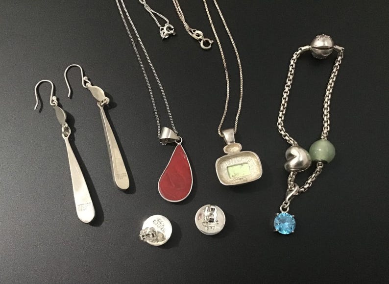 Puede incluir: Una colecci&oacute;n de joyas de plata que incluye pendientes, collares, una pulsera y pendientes de bot&oacute;n. Los collares presentan dise&ntilde;os de l&aacute;grima, cuadrados y colgantes. La pulsera tiene un dije de piedra preciosa azul. Los pendientes son largos.